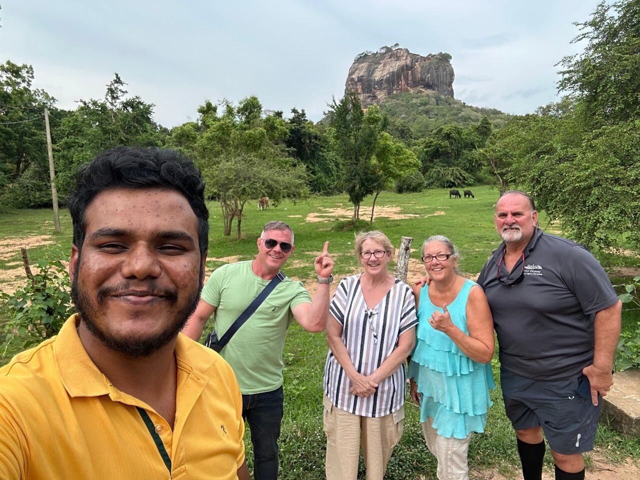 Happy group of travellers with the Kayeli Lanka guide and Sigiriya rock in the background