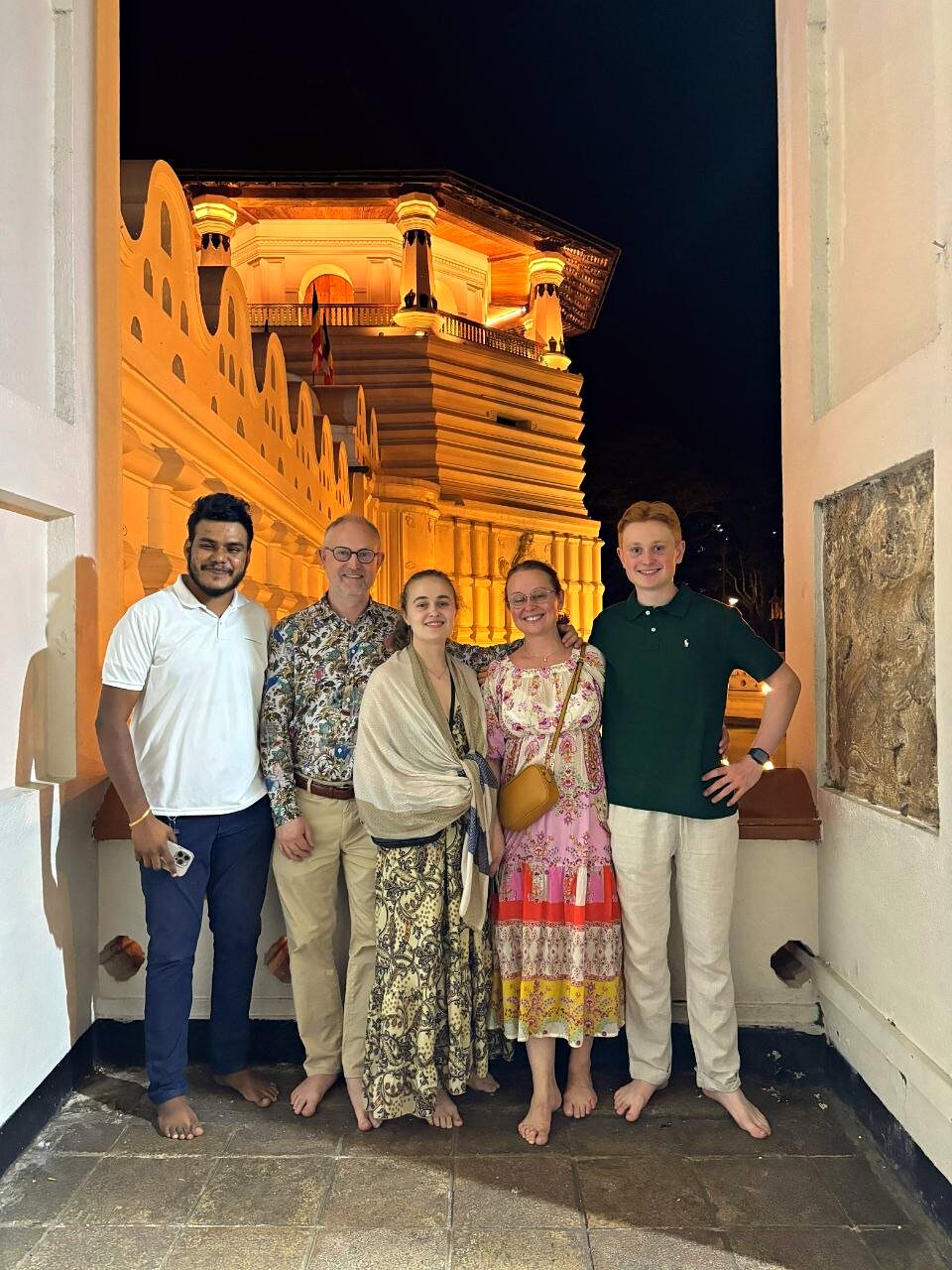Group of travellers with the guide at the illuminated Temple of the Tooth in Kandy