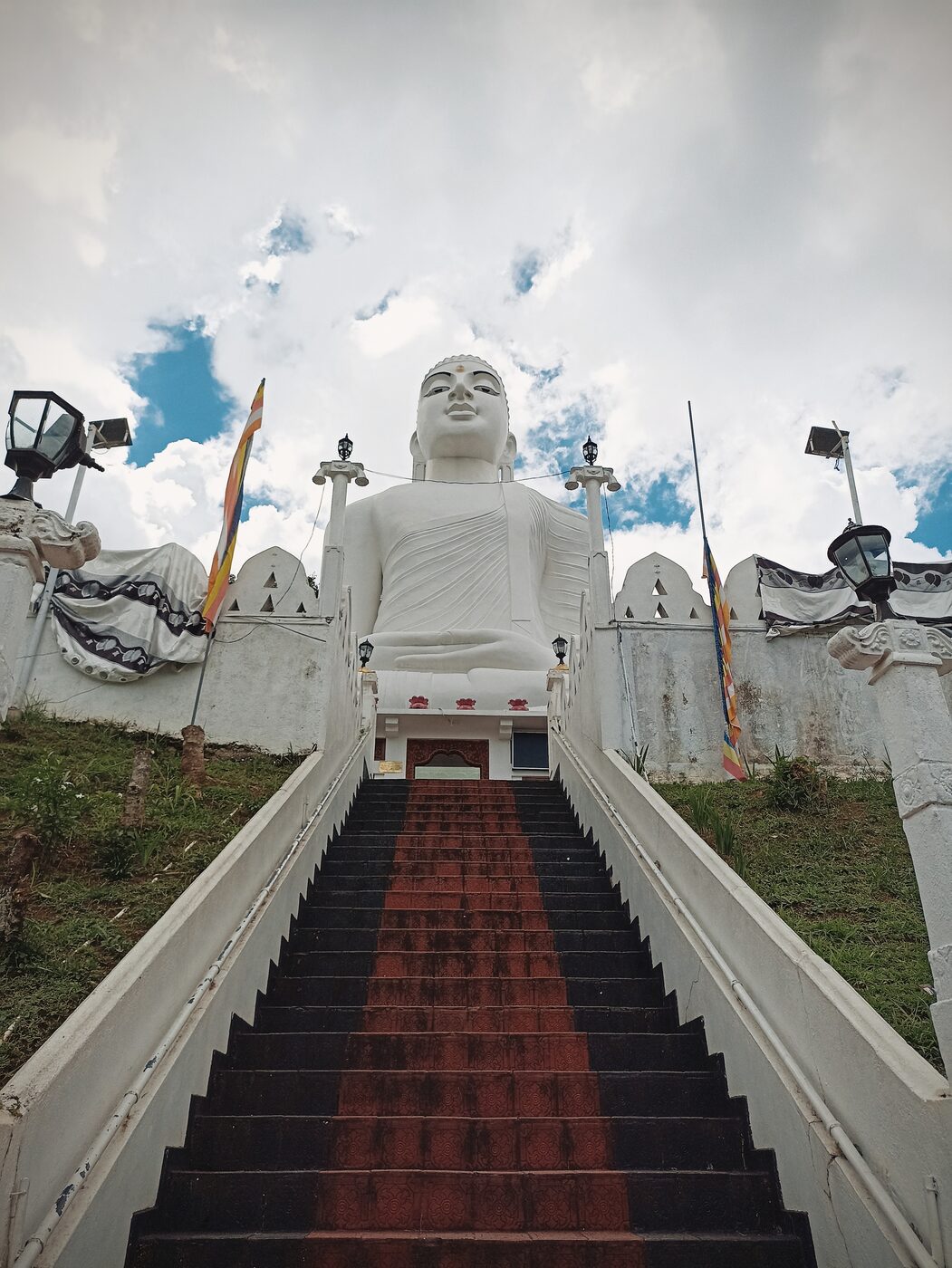 Large white Buddha statue reached by a long staircase in Kandy