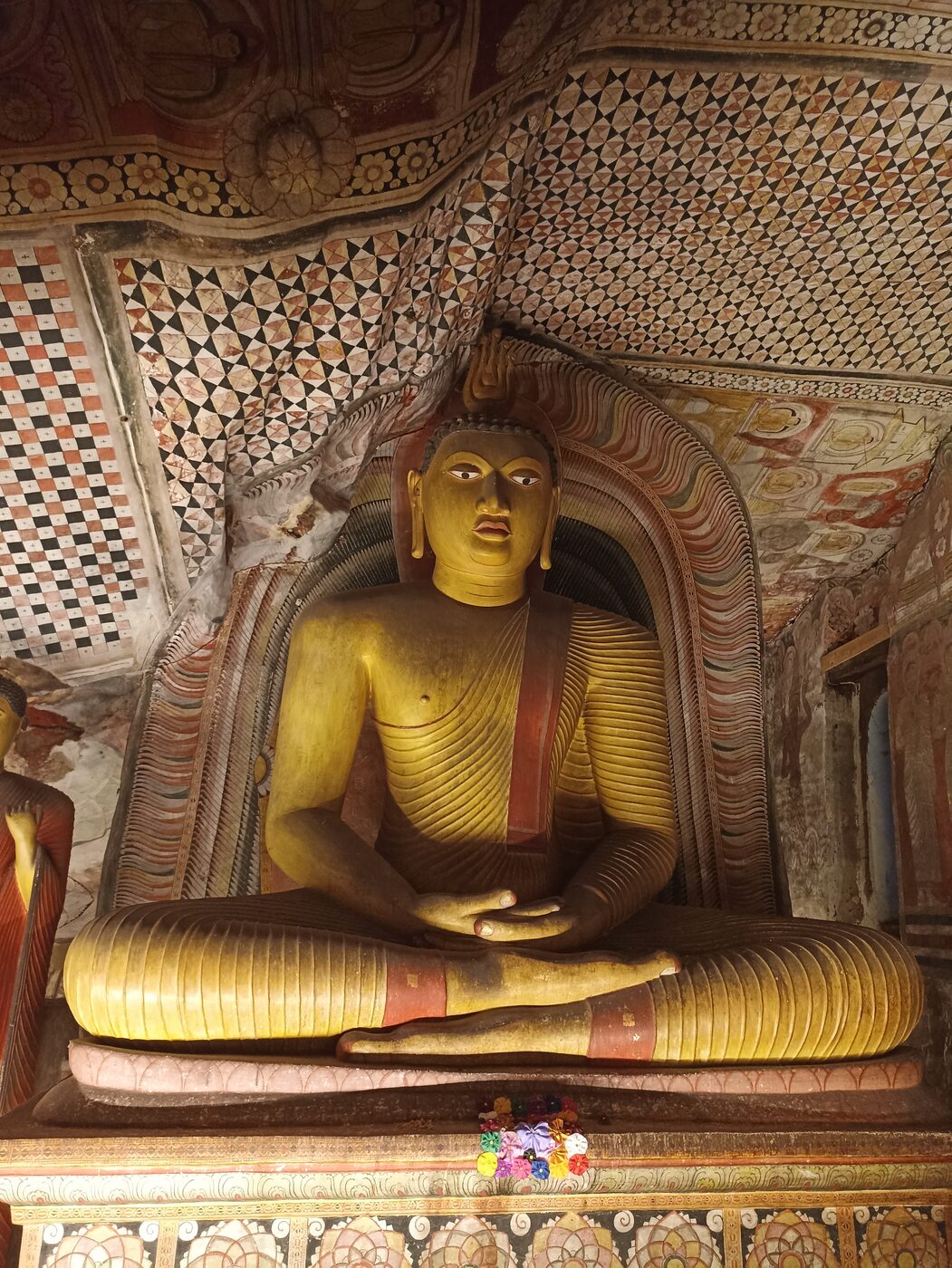 Golden seated Buddha statue inside the ornate Dambulla cave temple